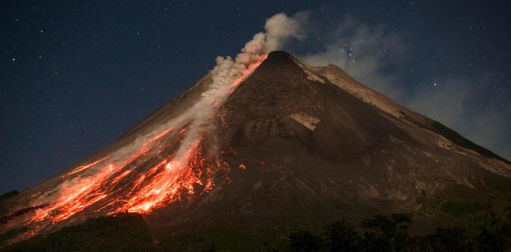La lava y los flujos piroclásticos brotan de la cima del monte Merapi durante una erupción, tal como se observa desde la aldea de Ngori, en Java Central, Indonesia.