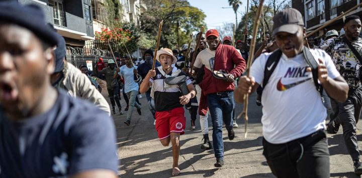 Los manifestantes corren detrás de personas que creen que son extranjeros indocumentados durante una manifestación de los movimientos "Marcha y Marcha" y Operación Dudula que marcan una fecha límite no oficial establecida por grupos liderados por ciudadanos para que los extranjeros indocumentados abandonen Sudáfrica, en Johannesburgo.