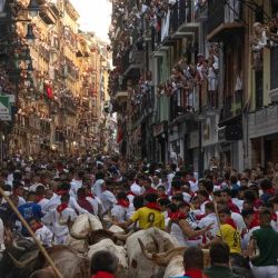 Los participantes corren delante de los toros de la ganadería Fuente Ymbro durante el primer encierro de las fiestas de San Fermín en Pamplona, norte de España. Miles de personas asisten cada año a las fiestas, que duran una semana, y a sus famosos encierros, en los que seis toros son liberados a las 8:00 de la mañana para correr desde su corral hasta la plaza de toros por las estrechas calles del casco antiguo, recorriendo una distancia de 850 metros. Los corredores que van delante intentan mantenerse cerca de los toros sin caerse ni ser corneados. | Foto:JORGE GUERRERO / AFP