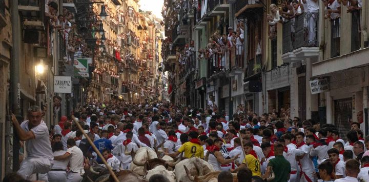 Los participantes corren delante de los toros de la ganadería Fuente Ymbro durante el primer encierro de las fiestas de San Fermín en Pamplona, norte de España. Miles de personas asisten cada año a las fiestas, que duran una semana, y a sus famosos encierros, en los que seis toros son liberados a las 8:00 de la mañana para correr desde su corral hasta la plaza de toros por las estrechas calles del casco antiguo, recorriendo una distancia de 850 metros. Los corredores que van delante intentan mantenerse cerca de los toros sin caerse ni ser corneados.