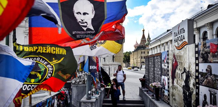 Varias personas visitaron un monumento improvisado en memoria de los combatientes caídos de la compañía militar privada Wagner en el centro de Moscú, convertido en un monumento general a las bajas militares rusas. En una de las banderas se puede ver el retrato del presidente ruso Vladimir Putin y, al fondo, la catedral de San Basilio.