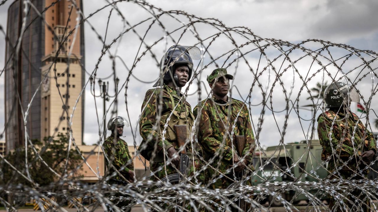 Agentes de la policía antidisturbios keniana montan guardia tras una barricada de alambre de púas mientras las autoridades imponen controles de carretera y el cierre parcial de las principales vías durante la marcha prevista de Saba Saba en el centro de Nairobi. La policía keniana prohibió la marcha, que conmemoraba un día anual de protesta, utilizando agentes de paisano y vehículos sin distintivos para dispersar incluso al pequeño grupo que logró reunirse. | Foto:LUIS TATO / AFP