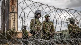 Agentes de la policía antidisturbios keniana montan guardia tras una barricada de alambre de púas mientras las autoridades imponen controles de carretera y el cierre parcial de las principales vías durante la marcha prevista de Saba Saba en el centro de Nairobi. La policía keniana prohibió la marcha, que conmemoraba un día anual de protesta, utilizando agentes de paisano y vehículos sin distintivos para dispersar incluso al pequeño grupo que logró reunirse.