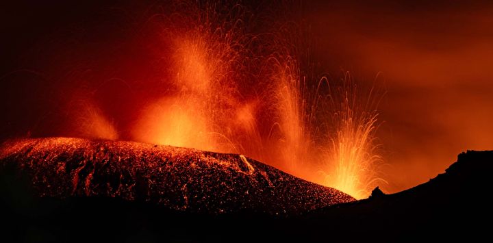 Una fotografía muestra la lava fluyendo del cráter durante una erupción del volcán Etna en Sicilia.