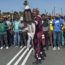 Manifestantes con atuendos tradicionales corean consignas durante una protesta del movimiento "Marcha y Marcha" en Mtwalume, al sur de Durban. El grupo ya había organizado marchas a nivel nacional y ha instado a sus seguidores a seguir manifestándose. El movimiento exige al gobierno que aplique medidas más estrictas contra la inmigración ilegal y que deporte a los extranjeros indocumentados. | Foto:RAJESH JANTILAL / AFP