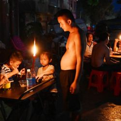 Un padre observa a sus hijos cenar a la luz de las velas frente a una casa en Gantang después de que las inundaciones provocadas por el colapso de un embalse en la región de Guangxi, al suroeste de China, dejaran sin electricidad. El número de muertos por las devastadoras inundaciones en la región de Guangxi, al sur de China, ascendió a 39, con nueve personas aún desaparecidas, según informaron los medios estatales, mientras los residentes se dedicaban a las labores de limpieza. | Foto:Greg Baker / AFP