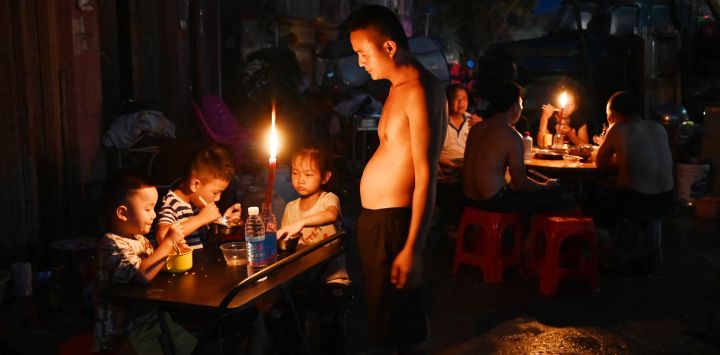 Un padre observa a sus hijos cenar a la luz de las velas frente a una casa en Gantang después de que las inundaciones provocadas por el colapso de un embalse en la región de Guangxi, al suroeste de China, dejaran sin electricidad. El número de muertos por las devastadoras inundaciones en la región de Guangxi, al sur de China, ascendió a 39, con nueve personas aún desaparecidas, según informaron los medios estatales, mientras los residentes se dedicaban a las labores de limpieza.
