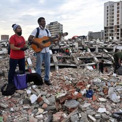 Residentes cantan himnos cristianos entre los escombros del edificio de Obras del Poder Popular (OPP) en Caraballeda, estado de La Guaira, Venezuela, tras los dos terremotos que azotaron la región. Los dos sismos que sacudieron Venezuela el 24 de junio habían dejado casi 4.500 muertos, mientras que gran parte de la población afectada seguía viviendo en campamentos, según cifras oficiales. | Foto:JUAN BARRETO / AFP