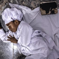 Un niño duerme junto a una Biblia durante un servicio religioso en la sede internacional de la Iglesia Celestial de Cristo en el barrio de Ketu, Lagos. | Foto:OLYMPIA DE MAISMONT / AFP