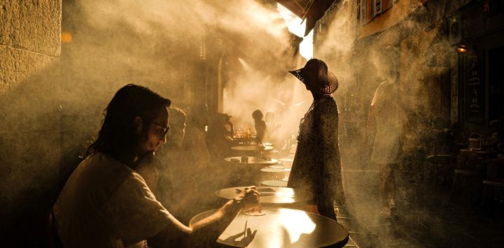 Varias personas permanecen de pie frente a una cafetería durante una ola de calor en la ciudad de Niza, en la Riviera francesa.