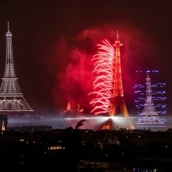 Fuegos artificiales y drones iluminan el cielo alrededor de la Torre Eiffel durante un espectáculo coreografiado con motivo del Día de la Bastilla en París, víspera del desfile anual del Día de la Bastilla en la capital francesa. | Foto:Martín Bureau / AFP