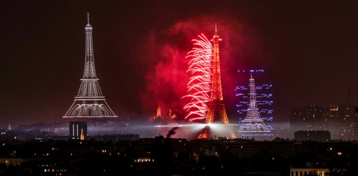 Fuegos artificiales y drones iluminan el cielo alrededor de la Torre Eiffel durante un espectáculo coreografiado con motivo del Día de la Bastilla en París, víspera del desfile anual del Día de la Bastilla en la capital francesa.