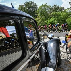 El pelotón de ciclistas pasa junto a un coche clásico estacionado a lo largo del recorrido de la 11.ª etapa de la 113.ª edición del Tour de Francia, un circuito de 161,3 km entre Vichy y Nevers, en el centro de Francia. | Foto:LOIC VENANCE / AFP