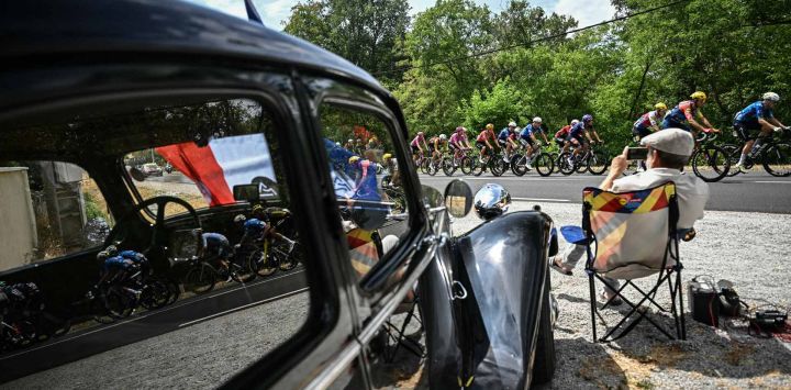 El pelotón de ciclistas pasa junto a un coche clásico estacionado a lo largo del recorrido de la 11.ª etapa de la 113.ª edición del Tour de Francia, un circuito de 161,3 km entre Vichy y Nevers, en el centro de Francia.