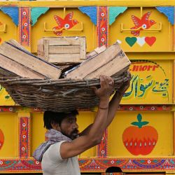 Un trabajador transporta cestas de fruta en un mercado mayorista de Lahore, Pakistán. | Foto:Arif Ali / AFP