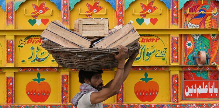 Un trabajador transporta cestas de fruta en un mercado mayorista de Lahore, Pakistán.