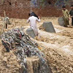 Residentes caminan entre el agua de la inundación tras las fuertes lluvias monzónicas en Landi Kotal, en la provincia de Khyber Pakhtunkhwa, Pakistán. | Foto:Abdul Majeed / AFP
