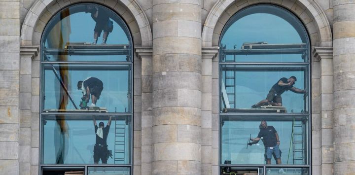Obreros limpian una ventana del edificio del Reichstag, sede del Bundestag (cámara baja del parlamento alemán), en Berlín.