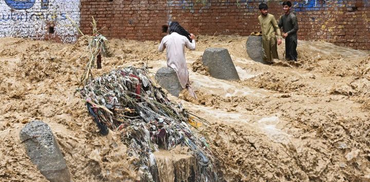 Residentes caminan entre el agua de la inundación tras las fuertes lluvias monzónicas en Landi Kotal, en la provincia de Khyber Pakhtunkhwa, Pakistán.
