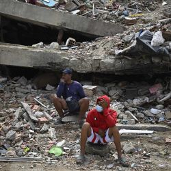 Residentes se sientan entre los escombros de un edificio residencial que se derrumbó tras los terremotos del 24 de junio, en Caraballeda, Venezuela. | Foto:Federico Parra / AFP