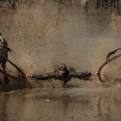 Un jinete se equilibra sobre un arado de madera adaptado para la carrera, sujetando y mordiendo a veces las colas de dos toros para guiarlos a través de un arrozal inundado, durante el Pacu Jawi, un evento tradicional de carreras de toros, en la aldea de Simabur, regencia de Tanah Datar, Sumatra Occidental, Indonesia. | Foto:Yasuyoshi Chiba / AFP