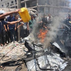 Un palestino desplazado intenta apagar el fuego de un vehículo en el lugar de un ataque israelí en la ciudad de Gaza. La violencia ha continuado en Gaza a pesar del alto el fuego. | Foto:OMAR AL-QATTAA / AFP