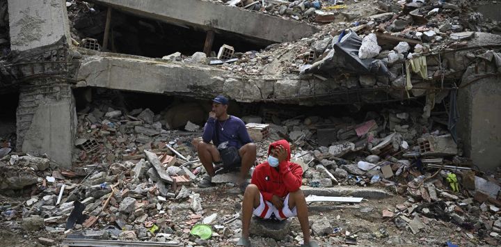 Residentes se sientan entre los escombros de un edificio residencial que se derrumbó tras los terremotos del 24 de junio, en Caraballeda, Venezuela.
