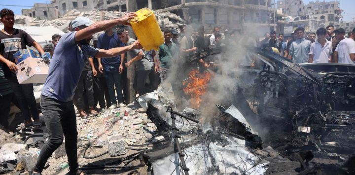 Un palestino desplazado intenta apagar el fuego de un vehículo en el lugar de un ataque israelí en la ciudad de Gaza. La violencia ha continuado en Gaza a pesar del alto el fuego.