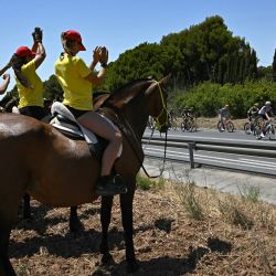 El Pelotón de ciclistas pasa junto a espectadores a caballo a lo largo del recorrido de la segunda etapa  de la 113.ª edición del Tpur de Francia, de 168 km, entre Tarragona y Barcelona, en el noroeste de España. | Foto:LOIC VENANCE / AFP