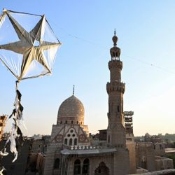 Un niño egipcio hace volar una cometa desde la azotea de su casa, frente al complejo funerario del sultán Qaytbay, durante la inauguración de la cúpula restaurada del mausoleo en El Cairo. | Foto:Khaled Desouki / AFP