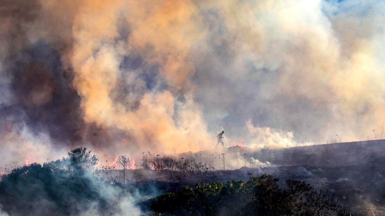 Palestinos caminan entre el humo mientras un incendio arde cerca de la aldea de Tell, adyacente al asentamiento israelí de Havat Gilad, al oeste de Nablus, en la Cisjordania ocupada, tras un presunto ataque incendiario perpetrado por colonos israelíes contra la aldea, según testigos presenciales. Varios incendios se desataron en el norte de Cisjordania, obligando a la evacuación del asentamiento israelí de Havat Gilad y dejando al menos dos bomberos heridos, según la policía y los equipos de rescate. | Foto:JAAFAR ASHTIYEH / AFP