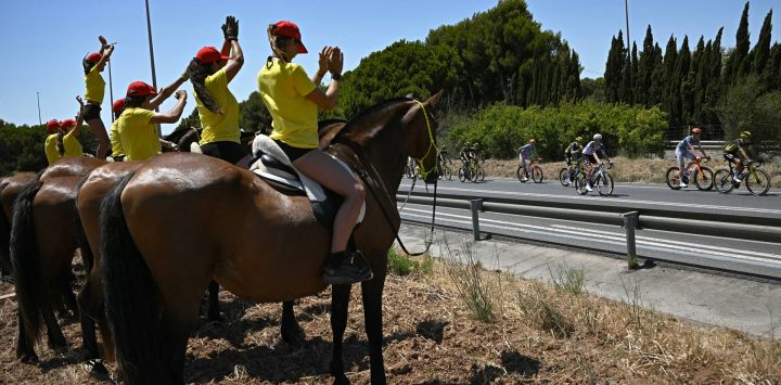 El Pelotón de ciclistas pasa junto a espectadores a caballo a lo largo del recorrido de la segunda etapa  de la 113.ª edición del Tpur de Francia, de 168 km, entre Tarragona y Barcelona, en el noroeste de España.