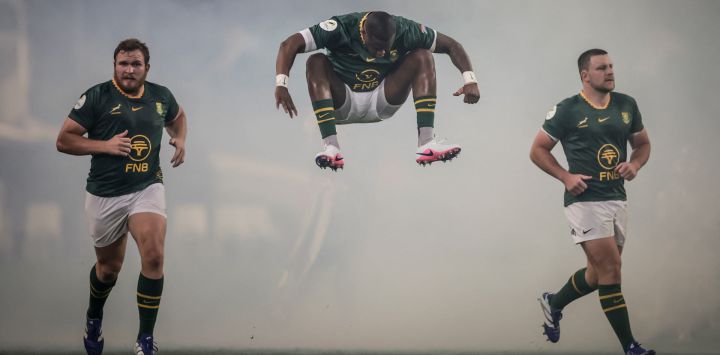 El zaguero sudafricano Aphelele Fassi salta al entrar al campo junto a los talonadores sudafricanos Jan-Hendrik Wessels y Andre-Hugo Venter durante el partido del Campeonato de Naciones de Rugby entre Sudáfrica y Gales en el estadio Kings Park de Durban.