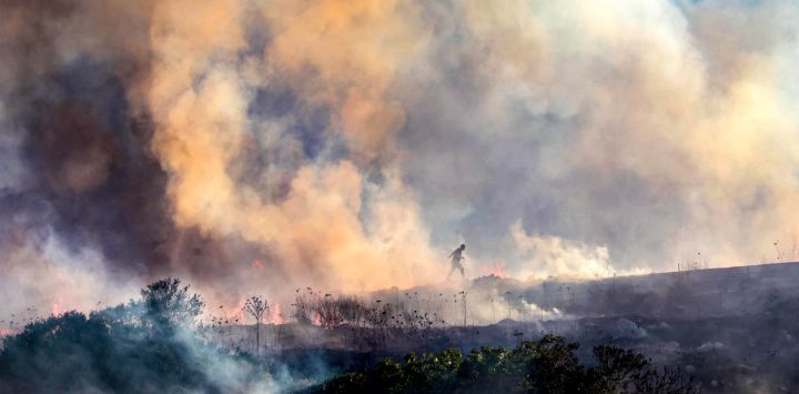 Palestinos caminan entre el humo mientras un incendio arde cerca de la aldea de Tell, adyacente al asentamiento israelí de Havat Gilad, al oeste de Nablus, en la Cisjordania ocupada, tras un presunto ataque incendiario perpetrado por colonos israelíes contra la aldea, según testigos presenciales. Varios incendios se desataron en el norte de Cisjordania, obligando a la evacuación del asentamiento israelí de Havat Gilad y dejando al menos dos bomberos heridos, según la policía y los equipos de rescate.