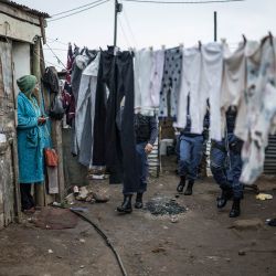 Una mujer observa cómo agentes del Servicio de Policía de Sudáfrica abandonan la vivienda de un residente sospechoso de albergar objetos robados en el municipio de Pellsrus, en Jeffreys Bay. La policía sudafricana informó que había arrestado a 69 personas tras una protesta antiinmigrante en la costa sureste del país que derivó en saqueos y dejó al menos una persona hospitalizada. Sudáfrica se ha visto sacudida durante semanas por protestas y disturbios contra inmigrantes indocumentados, lo que ha provocado que decenas de miles huyan del país. | Foto:MARCO LONGARI / AFP