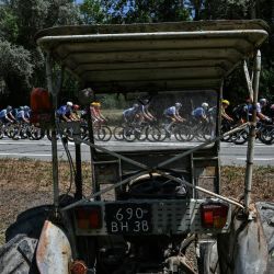 El pelotón de ciclistas pasa junto a un tractor al borde de la carretera durante la 18.ª etapa de la 113.ª edición del Tour de Francia, un recorrido de 185,2 km entre Voiron y Orcières-Merlette en los Alpes franceses. | Foto:JEFF PACHOUD / AFP