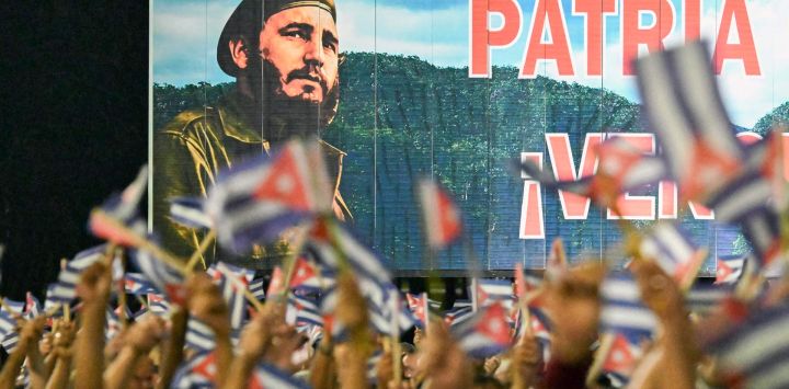 Cubanos ondean banderas de papel frente a una valla publicitaria con la imagen del fallecido líder Fidel Castro durante la celebración del 73.º aniversario del asalto guerrillero al Cuartel Moncada, liderado por Fidel Castro y considerado el inicio de la Revolución Cubana, en Pinar del Río, Cuba. Díaz-Canel denunció la "política genocida" de Washington hacia Cuba, acusando a Estados Unidos de intentar "apropiarse del país" mientras el presidente Donald Trump intensifica una estrategia de máxima presión contra la isla, junto con el embargo impuesto en 1962.