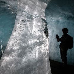 Esta fotografía muestra a un turista tomando fotos de una columna de hielo en la ahora mucho más pequeña cueva de hielo del glaciar Ródano, en proceso de deshielo, sobre Gletsch, en los Alpes suizos. Tras el calor extremo de junio y julio, el glaciar Ródano de Suiza ha perdido más de cuatro metros de hielo en un solo mes, según el glaciólogo Matthias Huss, director de la Red Suiza de Monitoreo de Glaciares (GLAMOS), citado por la agencia de noticias suiza Keystone-SDA. El retroceso del glaciar, con un promedio de unos 10 centímetros por día, ha generado preocupación de que 2026 pueda igualar la pérdida récord de hielo registrada en 2022. | Foto:FABRICE COFFRINI / AFP