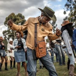 Los asistentes, ataviados con trajes de vaquero, bailan al ritmo de la música country durante las celebraciones del Día Internacional del Vaquero en el hipódromo de Ngong, en Nairobi, Kenia. Celebrado anualmente el Día Internacional del Vaquero conmemora la historia, la cultura y el legado perdurable de los vaqueros y vaqueras de todo el mundo. Si bien tiene sus raíces en las tradiciones de Norteamérica, la cultura vaquera y la música country han ganado cada vez más adeptos en algunas partes de África en los últimos años, especialmente en Kenia, donde la moda del Oeste, el baile en línea, la equitación y los eventos de música country han atraído a una creciente comunidad de aficionados. | Foto:LUIS TATO / AFP