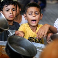 Niños hacen cola para recibir comida de un comedor social en el campamento de refugiados palestinos de Maghazi, en la Franja de Gaza central. | Foto:Eyad Baba / AFP