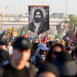 Peregrinos iraníes sostienen una imagen del primo y yerno del profeta Mahoma, el imán Ali ibn Abi Talib, con la inscripción reservada para él, 'Amir al-Mu'minin (Comandante de los Creyentes), mientras caminan por la carretera desde la ciudad santa chiíta de Nayaf hasta Karbala, a unos 80 kilómetros de distancia, para conmemorar el Arbaeen o 40 días de luto tras el martirio en la batalla de Karbala en el año 680 d. C. del imán Hussein, nieto del profeta. | Foto:Qassem al-Kaabi / AFP