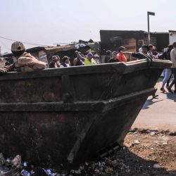 Un hombre se encuentra dentro de un contenedor de basura mientras miembros del movimiento March and March desfilan durante una manifestación semanal en Diepsloot, Johannesburgo, Sudáfrica. | Foto:MZINGENKOSI SIBANDA / AFP