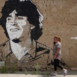 Un residente local camina junto a un mural que representa al futbolista argentino Diego Maradona en el pueblo de Staro Zhelezare. Desde 2015, estudiantes polacos se reúnen cada verano en el pueblo búlgaro de Staro Zhelezare para pintar grafitis en las paredes de las casas de sus apenas 400 habitantes. Los temas de las pinturas suelen estar relacionados con la actualidad política mundial. | Foto:NIKOLAY DOYCHINOV / AFP