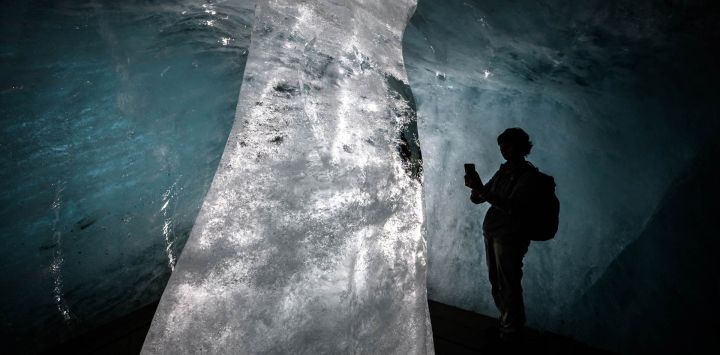 Esta fotografía muestra a un turista tomando fotos de una columna de hielo en la ahora mucho más pequeña cueva de hielo del glaciar Ródano, en proceso de deshielo, sobre Gletsch, en los Alpes suizos. Tras el calor extremo de junio y julio, el glaciar Ródano de Suiza ha perdido más de cuatro metros de hielo en un solo mes, según el glaciólogo Matthias Huss, director de la Red Suiza de Monitoreo de Glaciares (GLAMOS), citado por la agencia de noticias suiza Keystone-SDA. El retroceso del glaciar, con un promedio de unos 10 centímetros por día, ha generado preocupación de que 2026 pueda igualar la pérdida récord de hielo registrada en 2022.