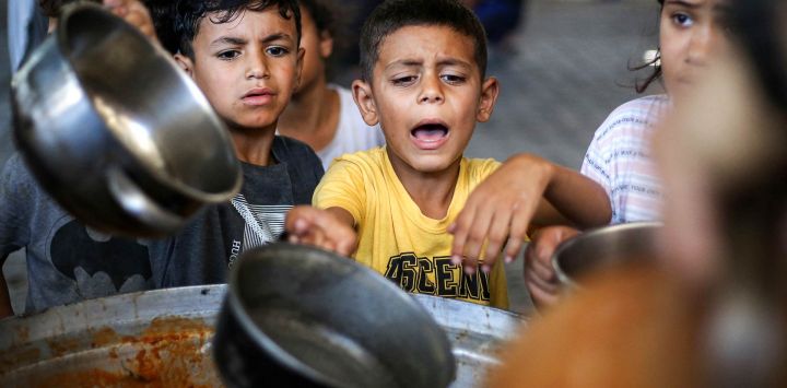 Niños hacen cola para recibir comida de un comedor social en el campamento de refugiados palestinos de Maghazi, en la Franja de Gaza central.