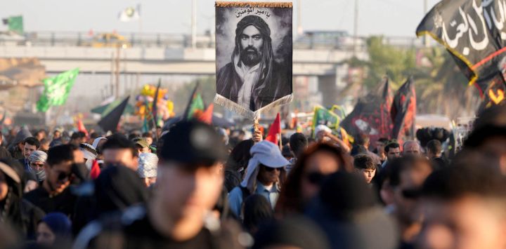 Peregrinos iraníes sostienen una imagen del primo y yerno del profeta Mahoma, el imán Ali ibn Abi Talib, con la inscripción reservada para él, 'Amir al-Mu'minin (Comandante de los Creyentes), mientras caminan por la carretera desde la ciudad santa chiíta de Nayaf hasta Karbala, a unos 80 kilómetros de distancia, para conmemorar el Arbaeen o 40 días de luto tras el martirio en la batalla de Karbala en el año 680 d. C. del imán Hussein, nieto del profeta.