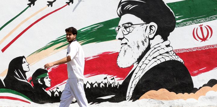 Un hombre pasa junto a un mural que representa al difunto líder supremo iraní, el ayatolá Ali Khamenei, en Teherán.