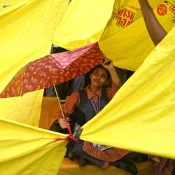 Una colegiala se resguarda bajo un paraguas en Jantar Mantar, Nueva Delhi, durante la protesta del Partido Janata de la Cucaracha (CJP, por sus siglas en inglés) para exigir la dimisión del ministro de Educación de la India, Dharmendra Pradhan, por presuntas irregularidades en el examen NEET. Los líderes del movimiento juvenil indio "Cucaracha" anunciaron que se reunirían con el gobierno después de que el primer ministro Narendra Modi prometiera reformas legales y un castigo rápido para los implicados en la filtración de los exámenes. | Foto:ARUN SANKAR / AFP