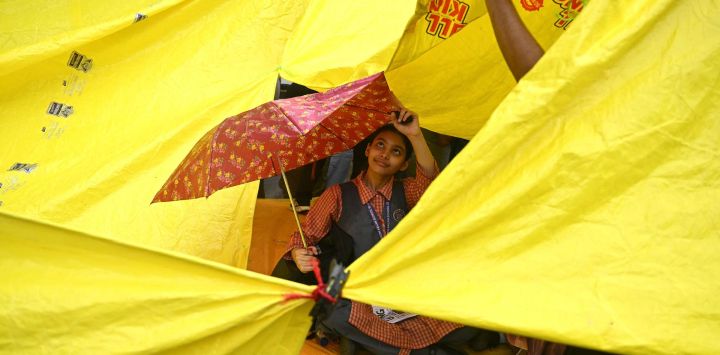 Una colegiala se resguarda bajo un paraguas en Jantar Mantar, Nueva Delhi, durante la protesta del Partido Janata de la Cucaracha (CJP, por sus siglas en inglés) para exigir la dimisión del ministro de Educación de la India, Dharmendra Pradhan, por presuntas irregularidades en el examen NEET. Los líderes del movimiento juvenil indio "Cucaracha" anunciaron que se reunirían con el gobierno después de que el primer ministro Narendra Modi prometiera reformas legales y un castigo rápido para los implicados en la filtración de los exámenes.