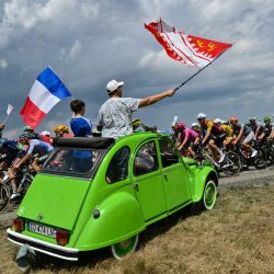Espectadores a bordo de un Citroën 2CV ondean banderas mientras el pelotón ciclista pasa durante la 14.ª etapa de la 113.ª edición del Tour de Francia, un recorrido de 155,3 km entre Mulhouse y Le Markstein, en las montañas de los Vosgos. | Foto:JEFF PACHOUD / AFP